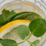 Top view of glass of fresh lemon alcohol cocktail placed on white background